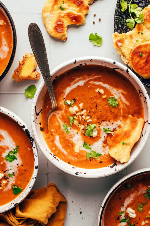 Bowls of our spicy pumpkin tomato soup with slices of vegan naan