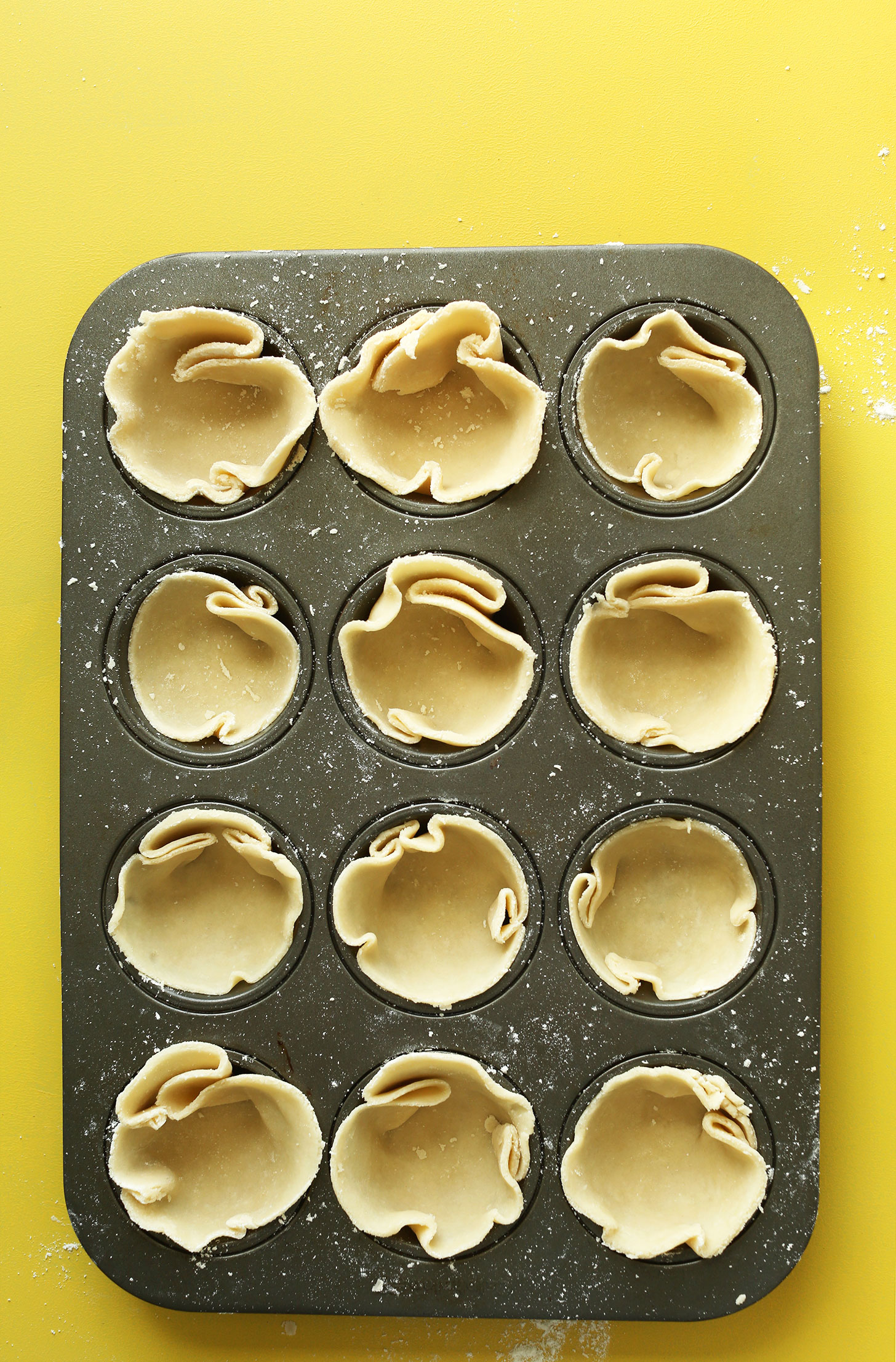 Muffin tin filled with Coconut Oil Pie Crust for making Vegan Mini Pumpkin Pies