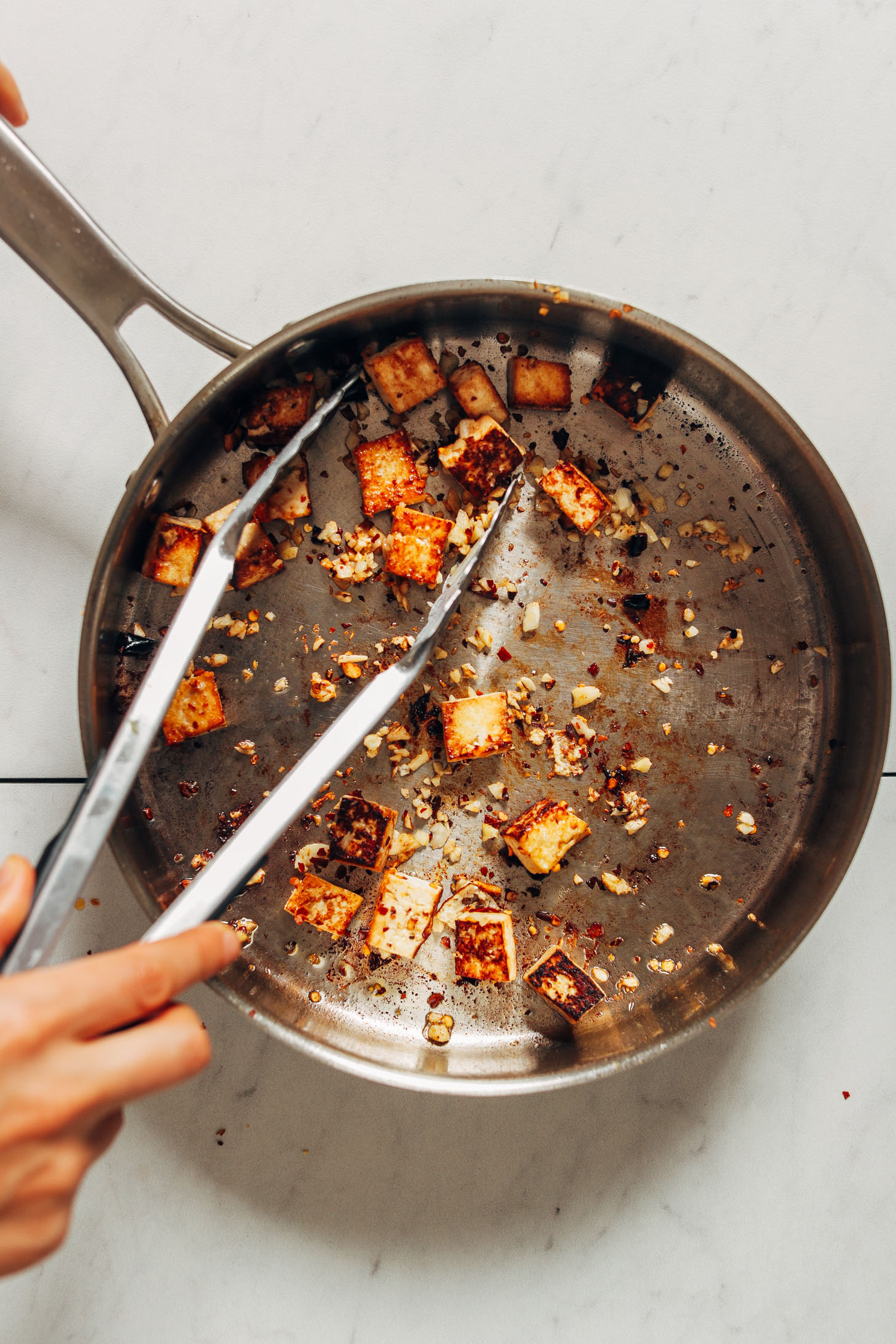 Sautéing tofu and garlic in a large skillet