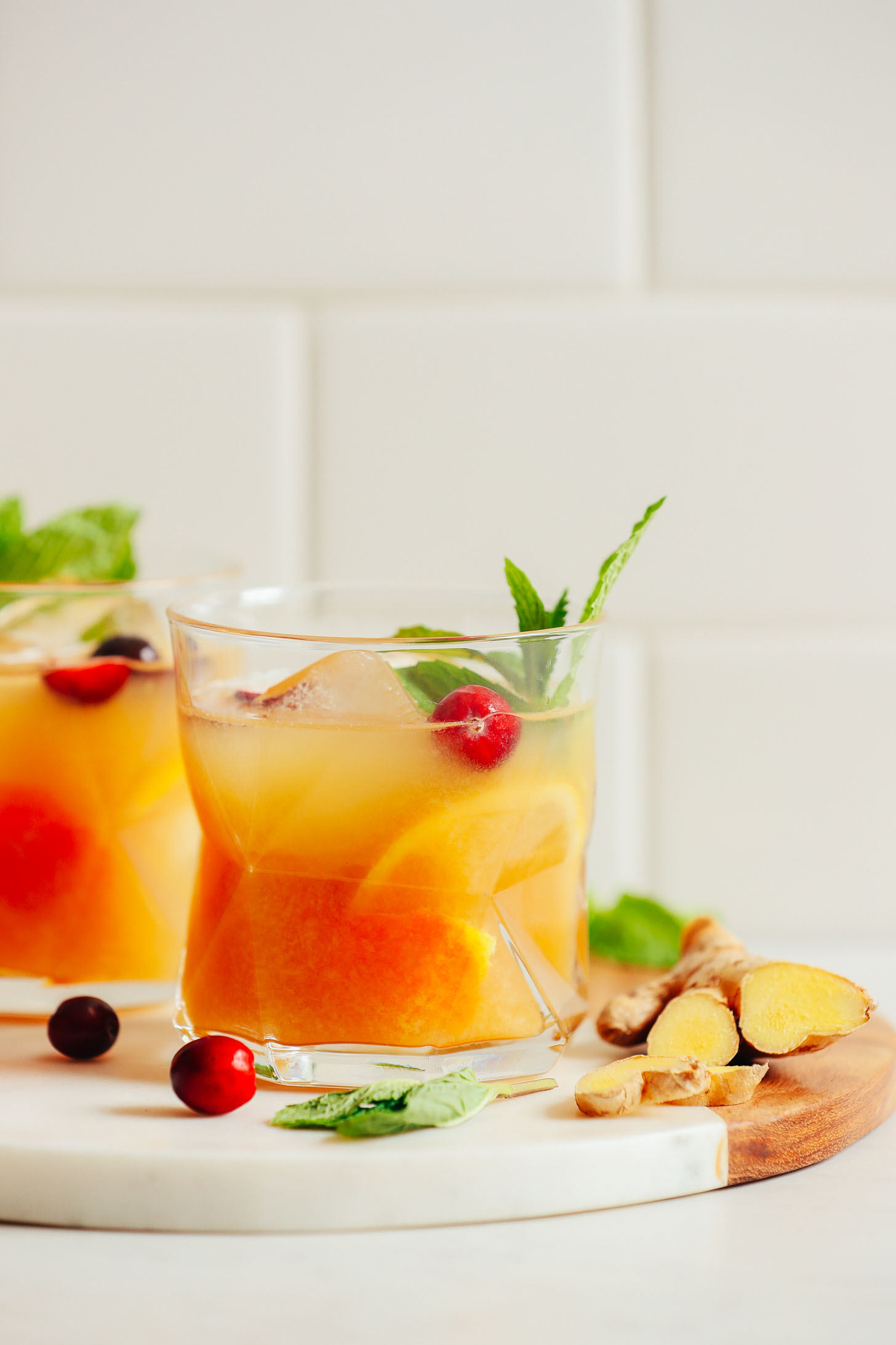 Close up shot of an Orange Whiskey Ginger with Mint and garnished with fresh cranberries