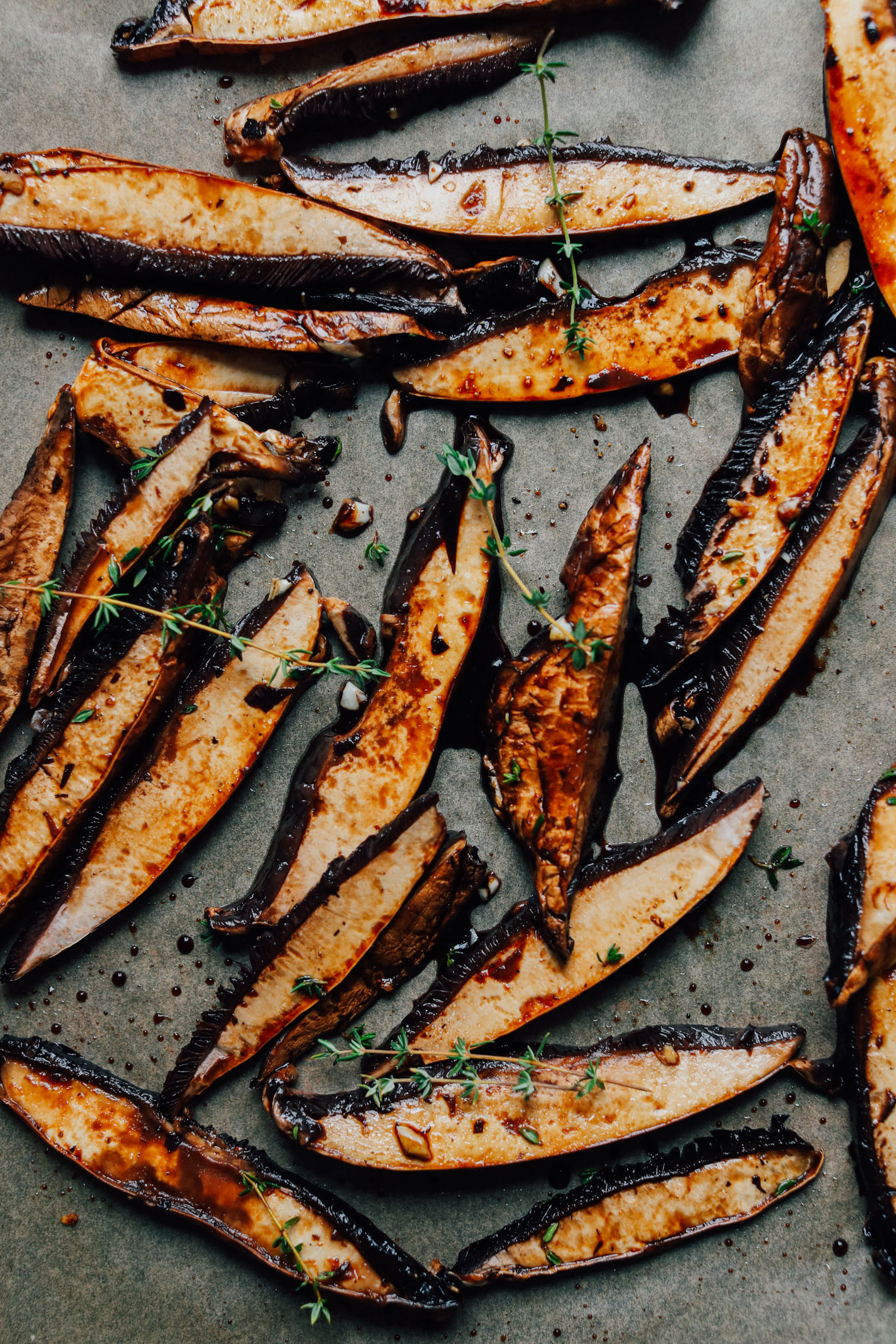 Beautifully roasted eggplant spears with fresh thyme on a baking sheet