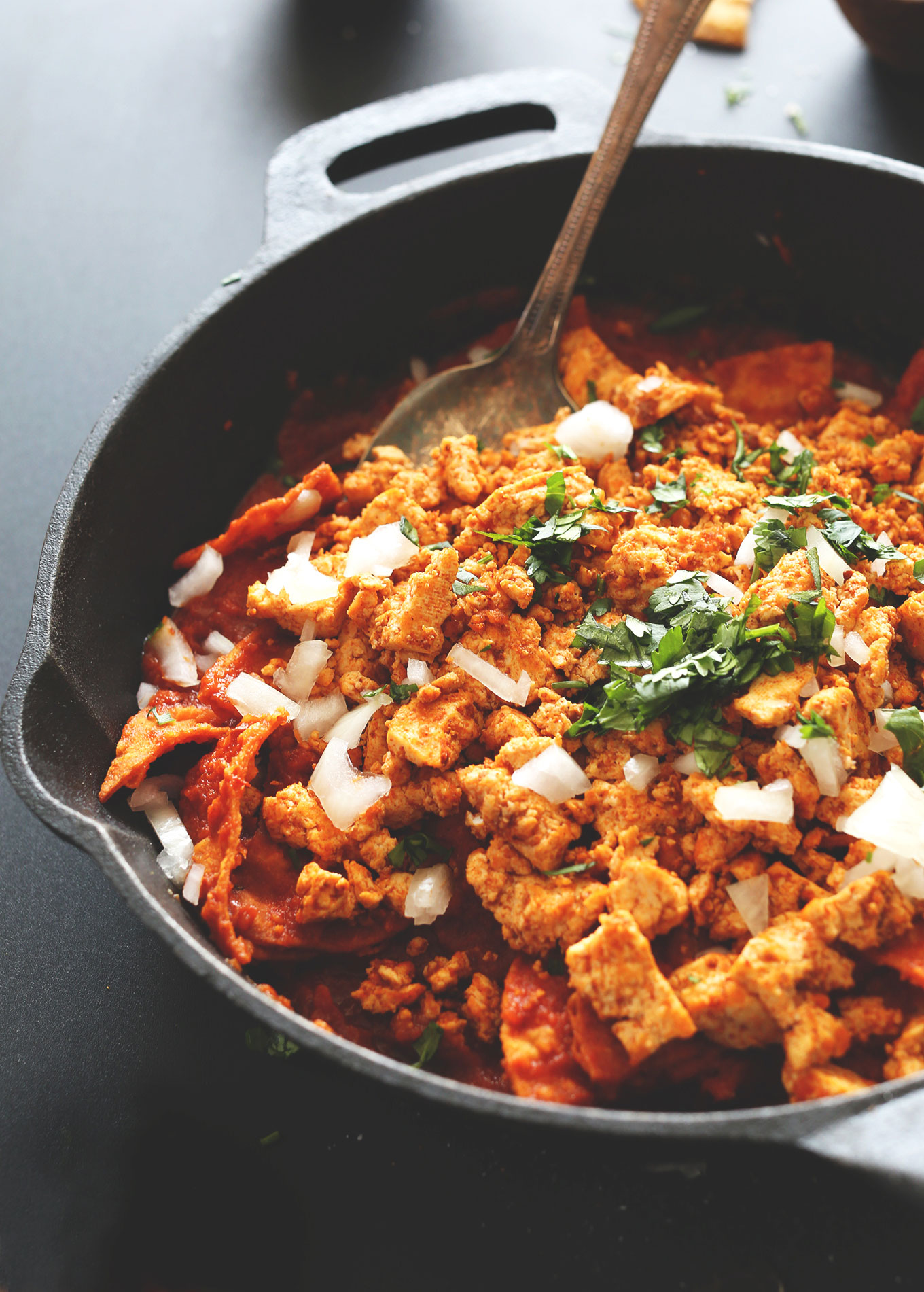 Stirring Vegan Chilaquiles in a cast-iron skillet