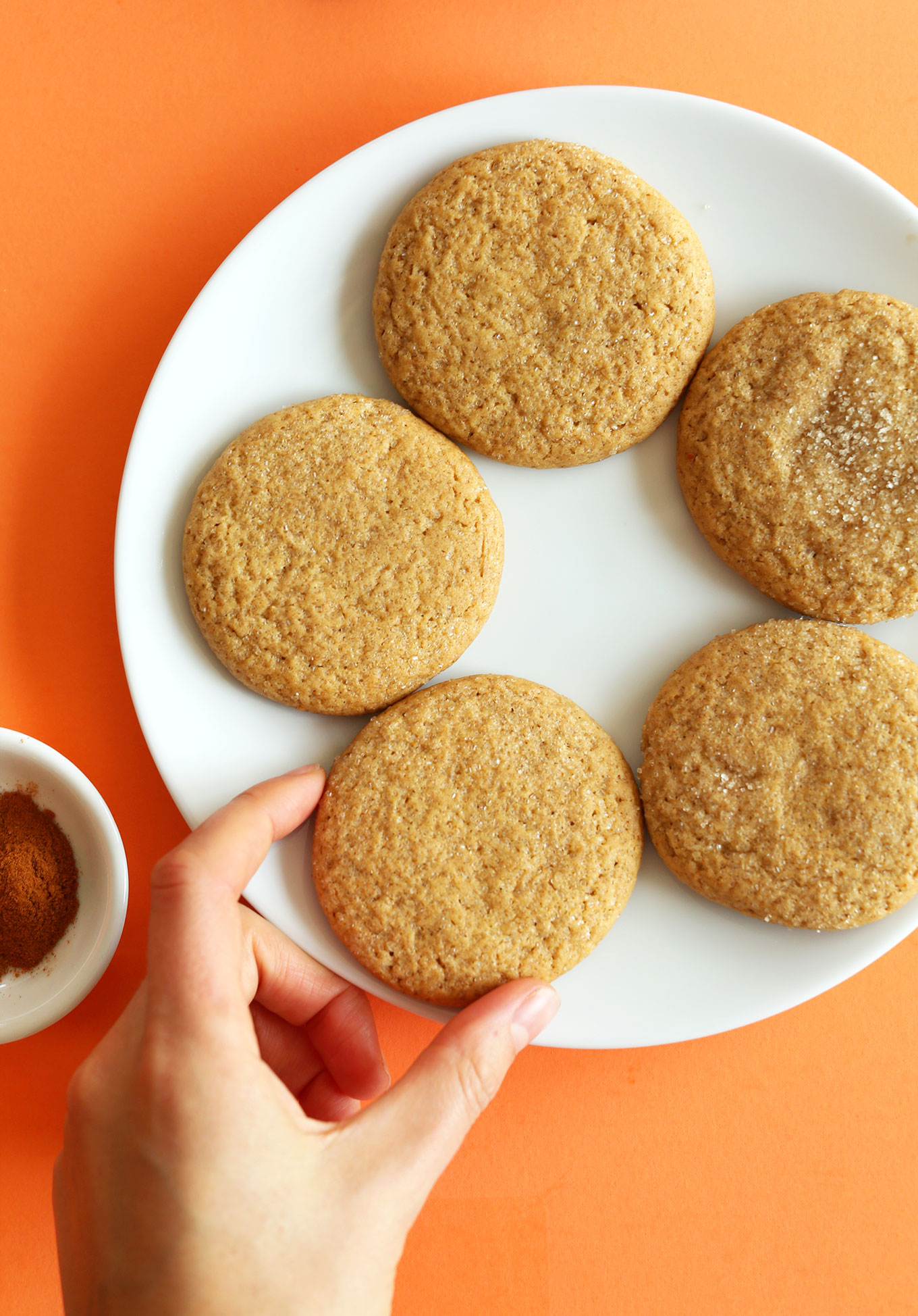 Grabbing a Vegan Pumpkin Sugar Cookie from a plate