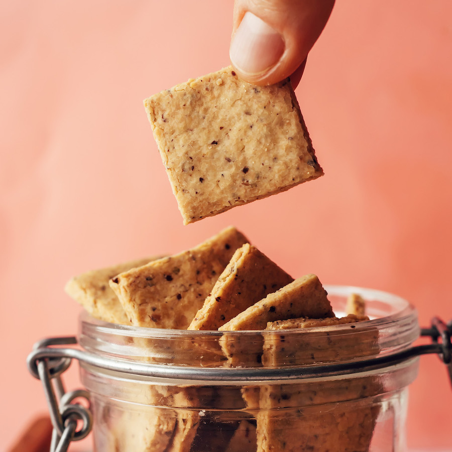 Holding a grain-free almond flour cracker above a jar