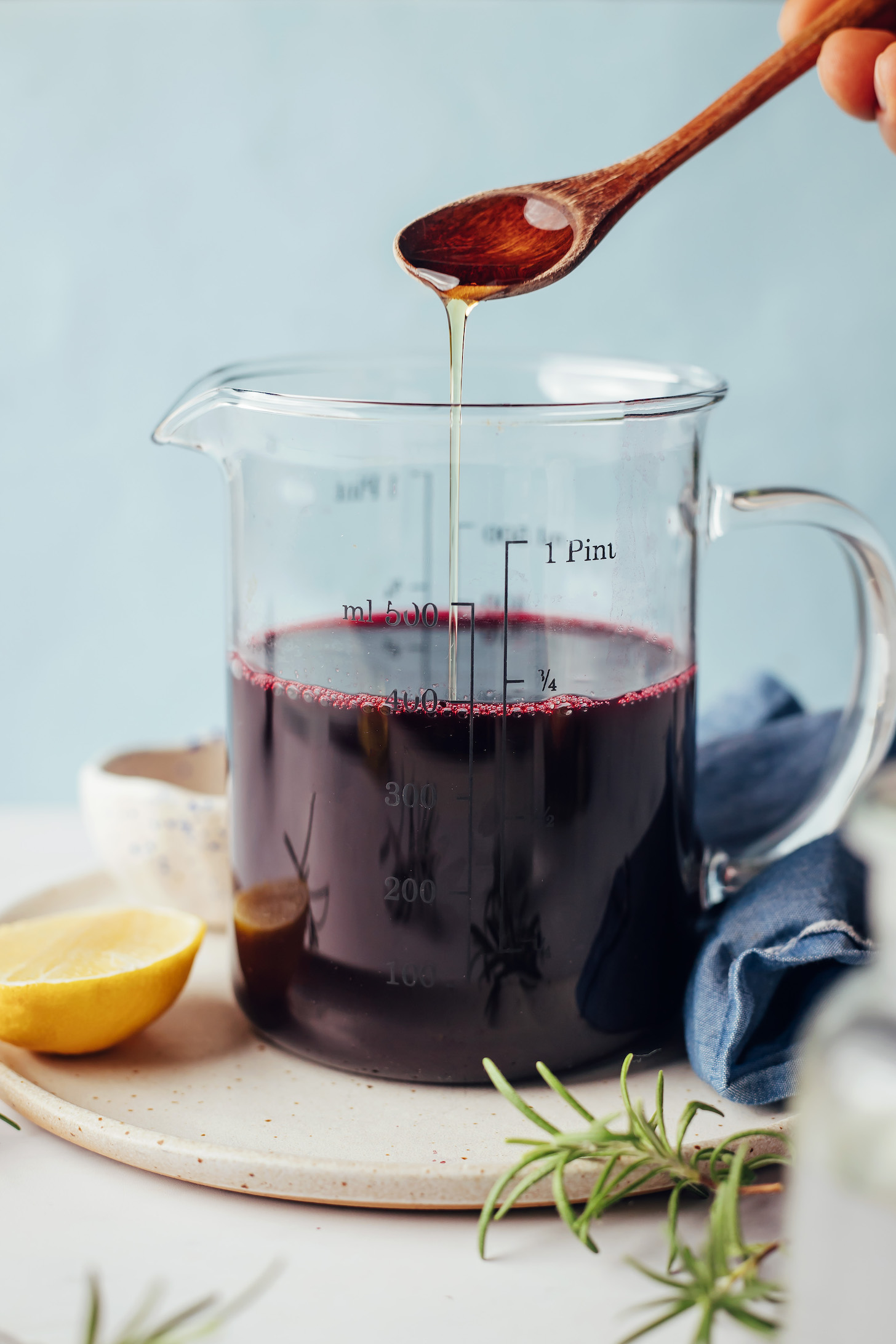 Maple syrup being added to a measuring cup of blueberry ginger syrup