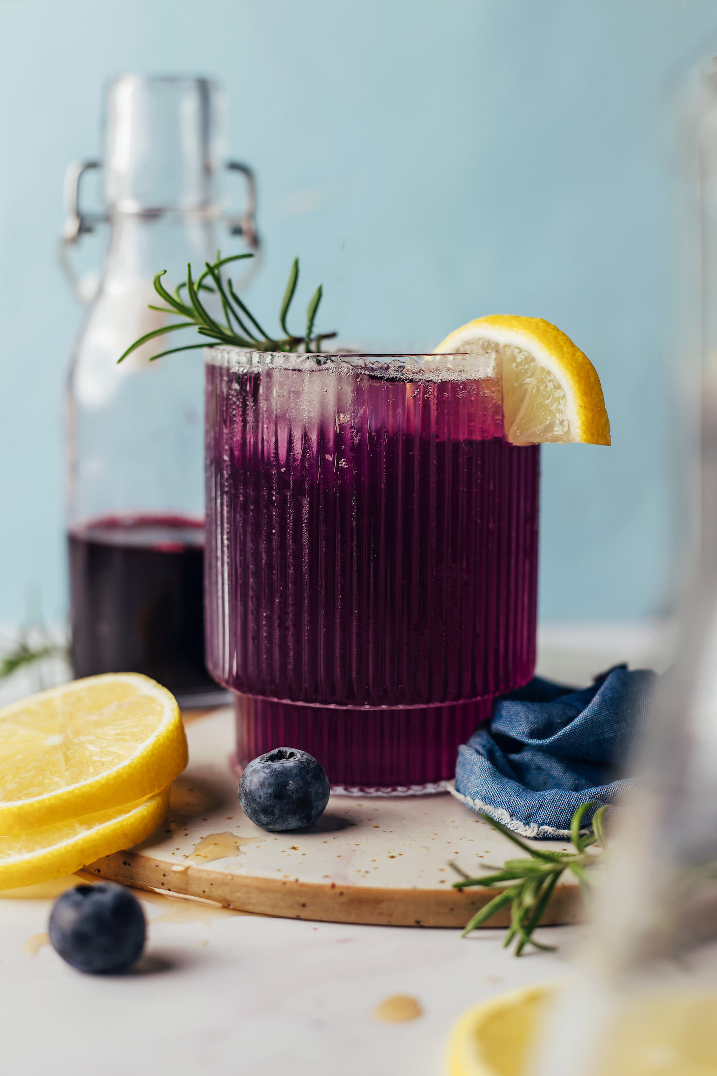 Blueberry simple syrup next to a sparkling non-alcoholic blueberry drink