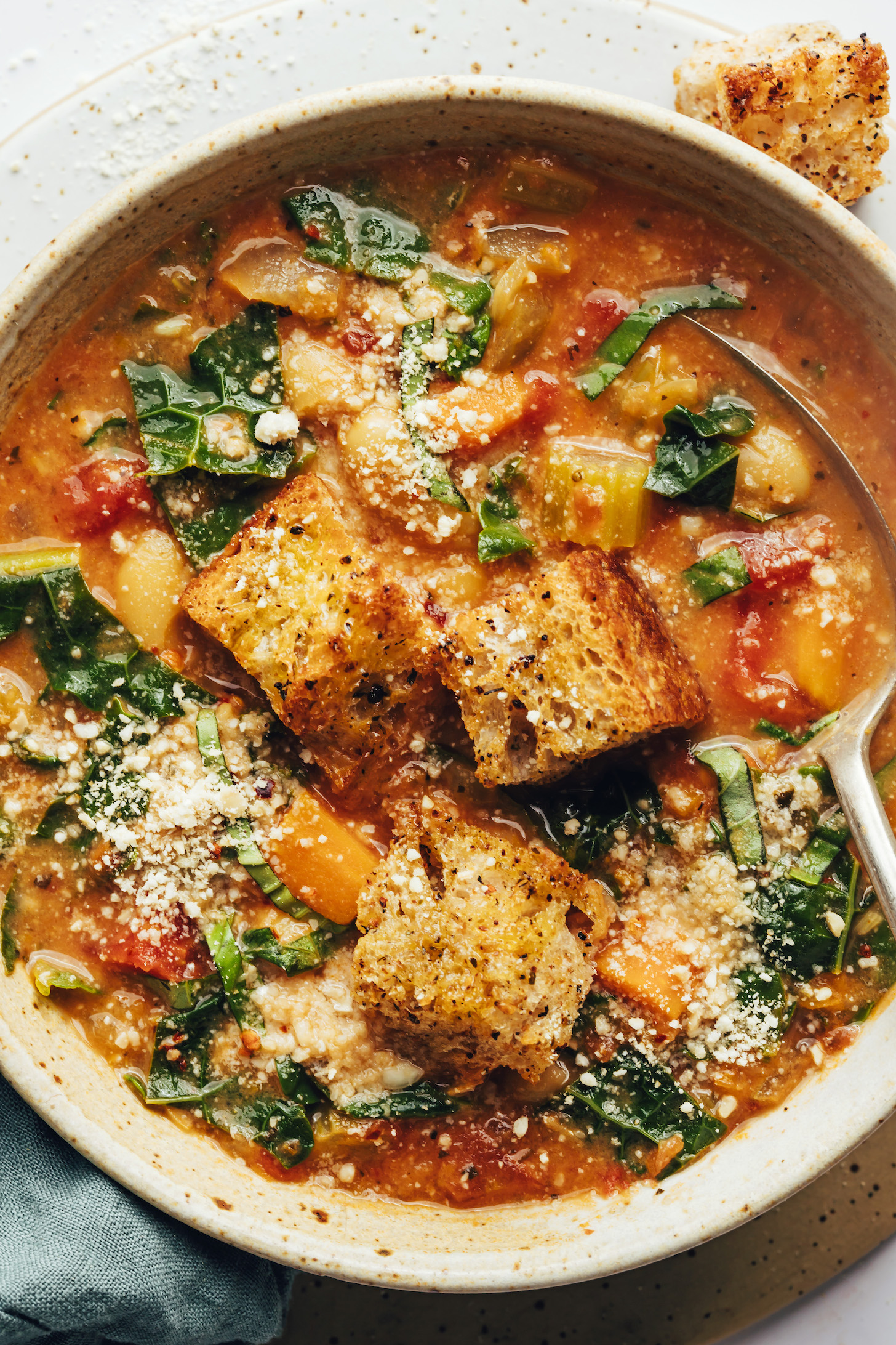 Bowl of creamy Tuscan white bean soup topped with croutons and vegan parmesan cheese