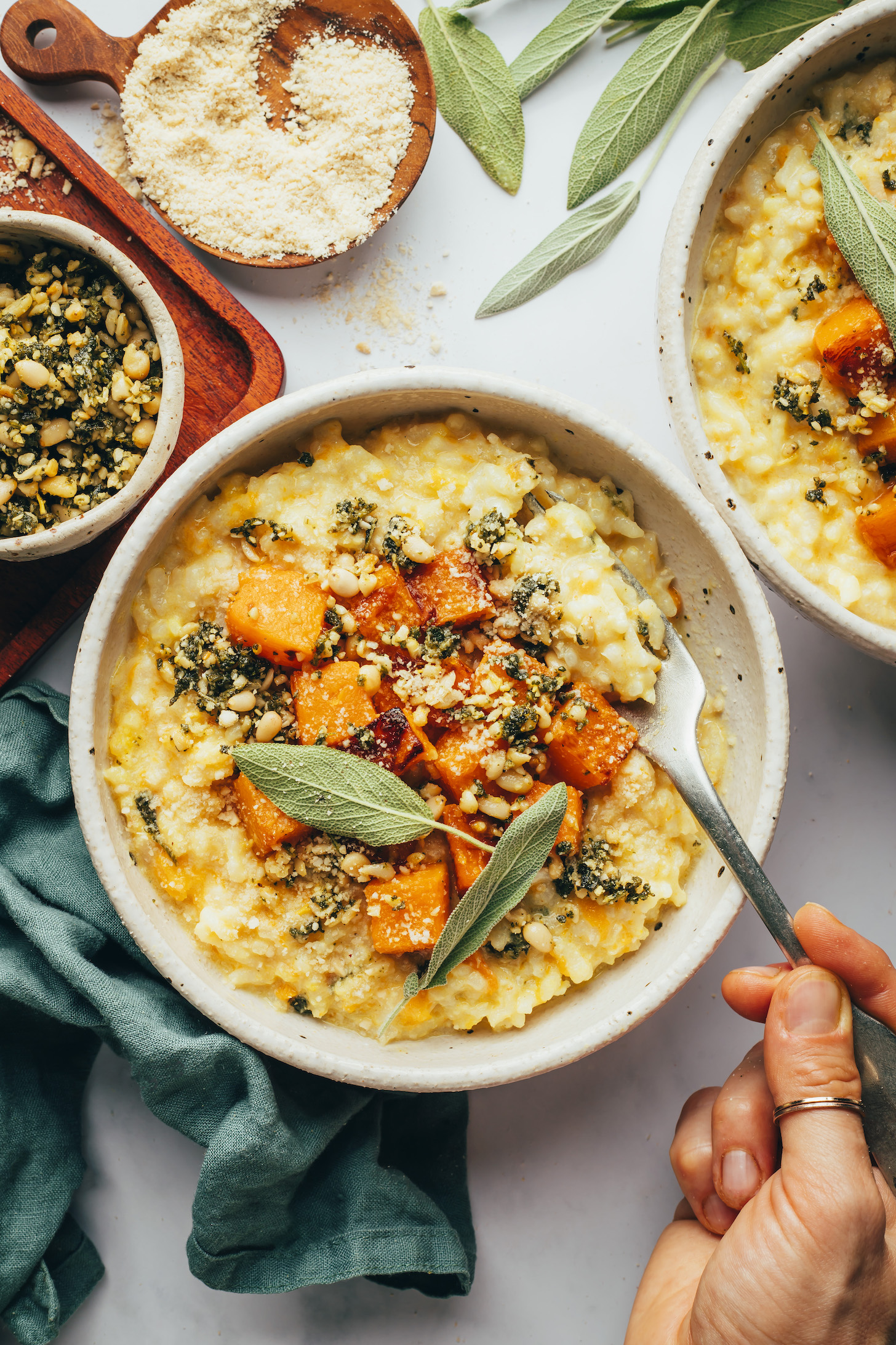 Hand holding a fork in a bowl of butternut squash risotto