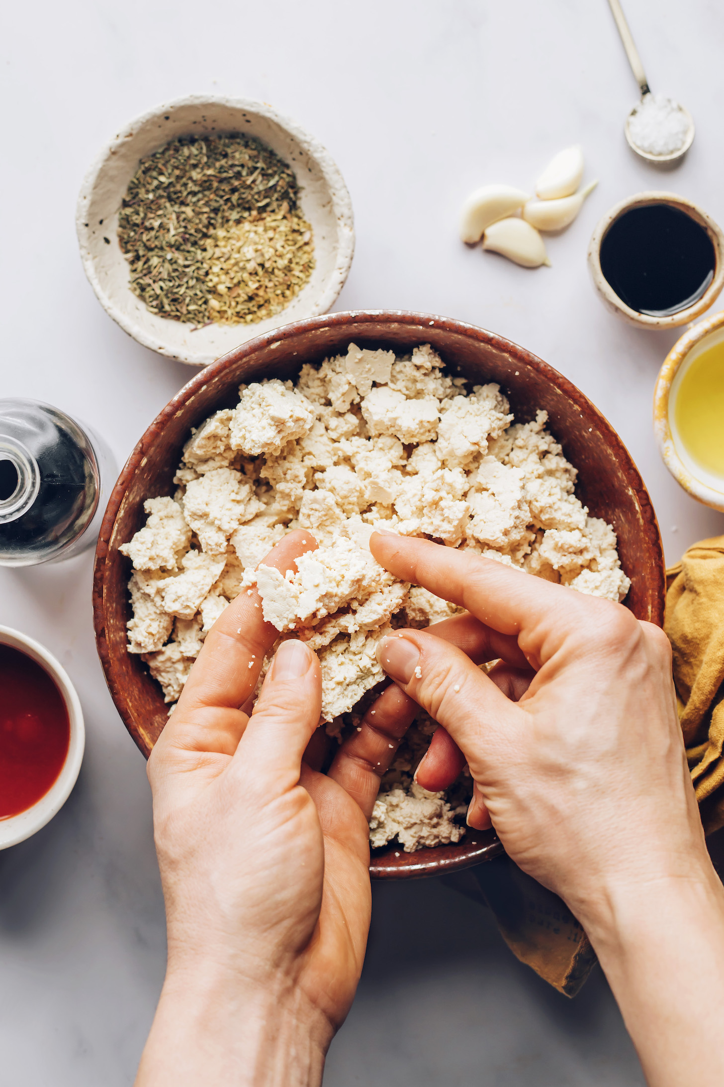 Crumbling tofu into bite-sized pieces in a bowl