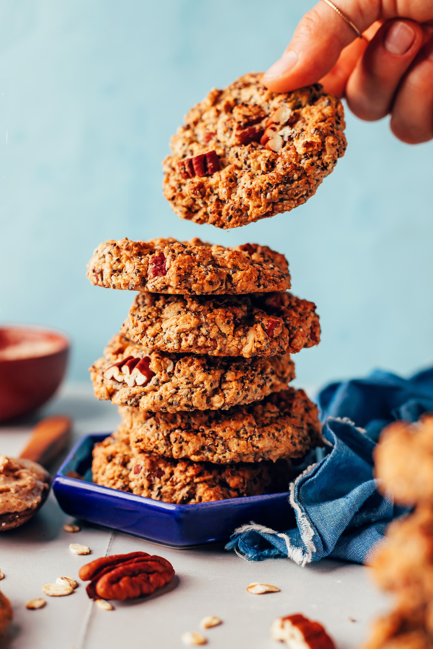 Picking up a vegan gluten-free chai-spiced oatmeal cookie from a stack of cookies