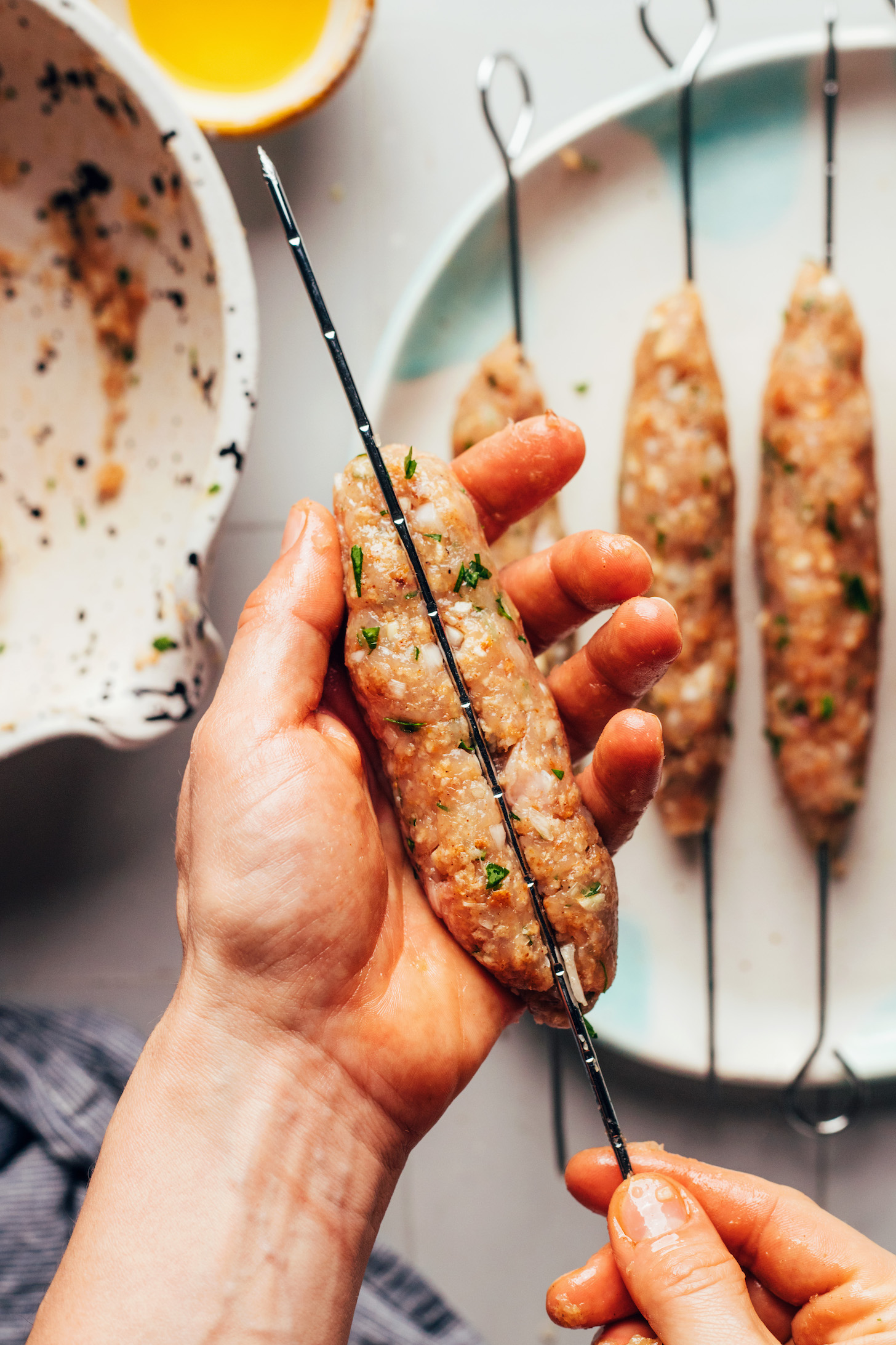 Placing chicken kofta around a metal skewer