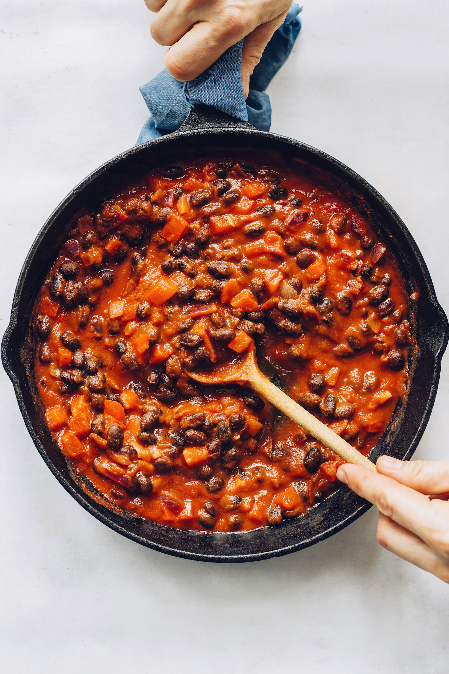 Stirring a pan of black beans, onion, bell pepper, and enchilada sauce