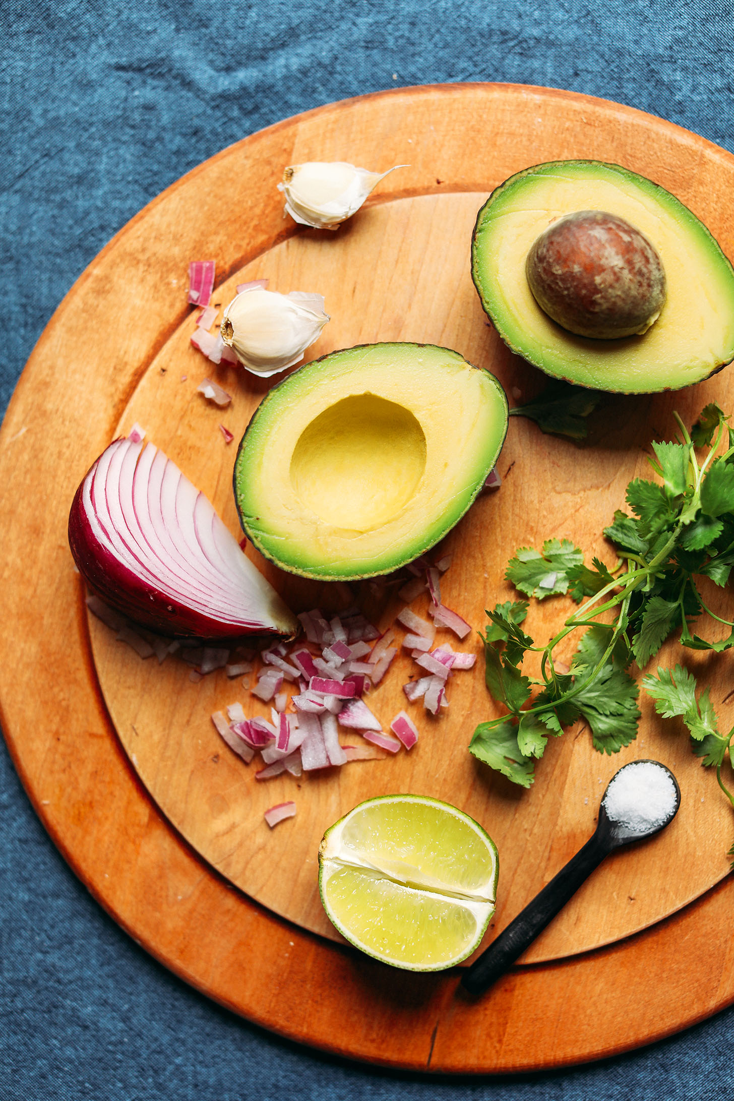 Wood cutting board with ingredients for making Garlicky Guacamole