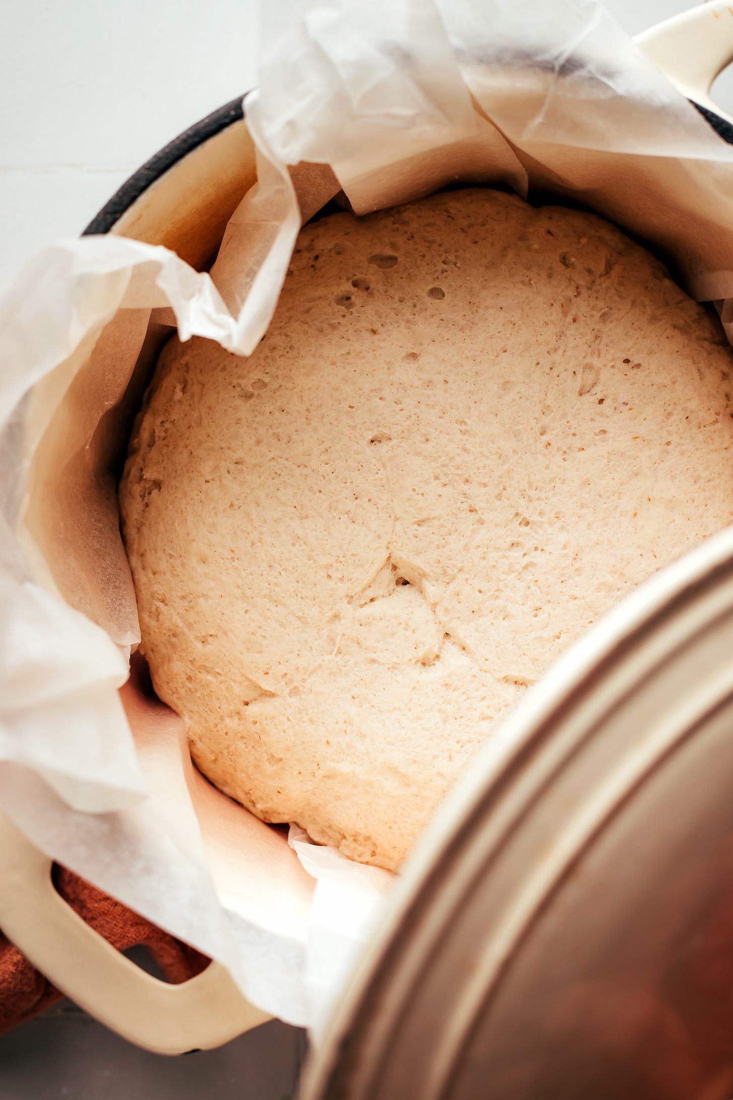 Gluten-free bread in a Dutch oven with parchment paper around it before baking