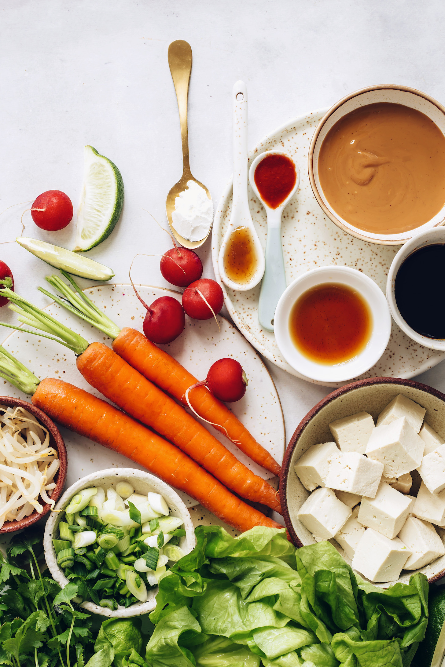 Carrots, radish, green onion, bean sprouts, lettuce, tofu, cornstarch, peanut butter, chili garlic sauce, maple syrup, toasted sesame oil, and tamari