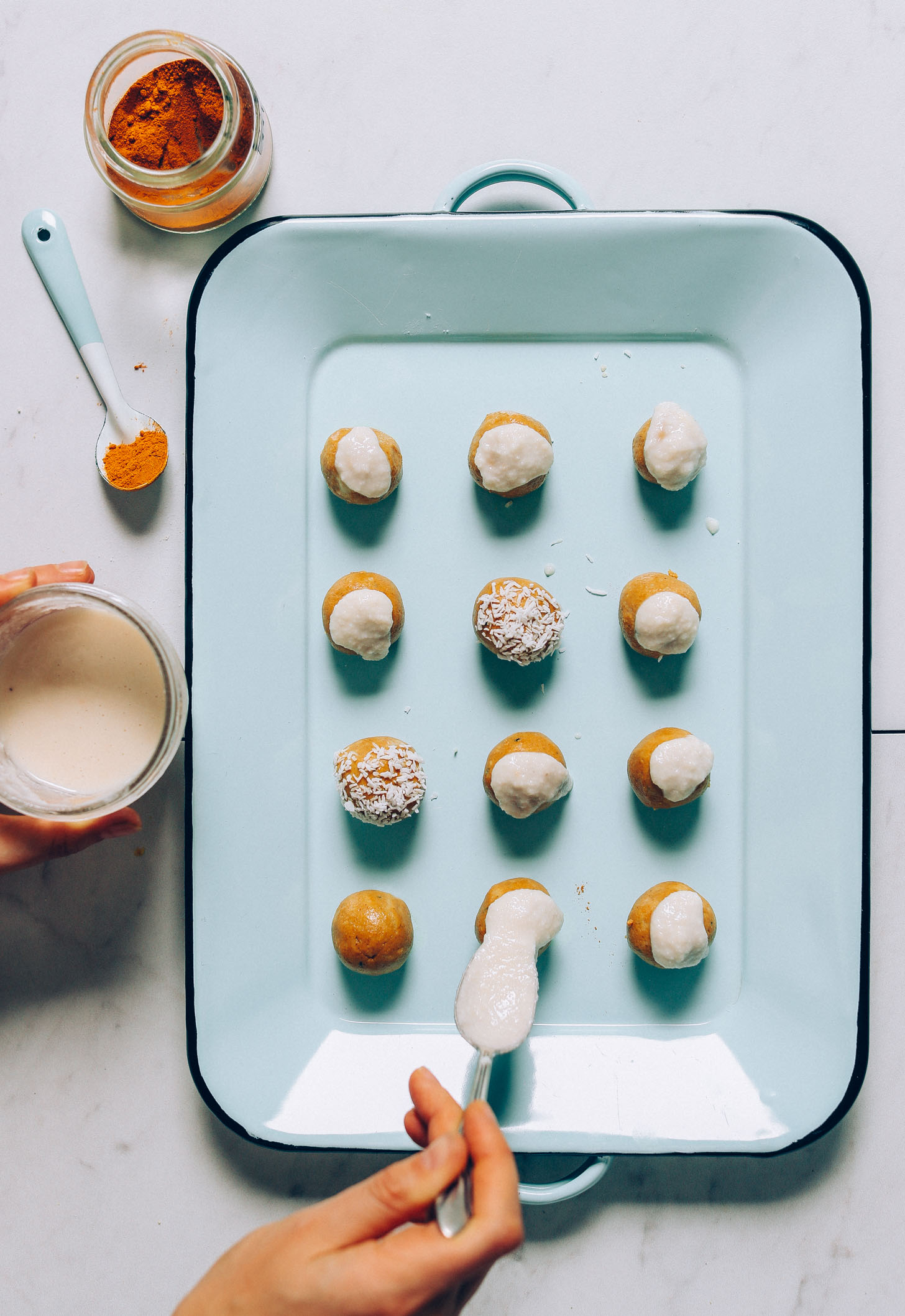 An overhead image of golden milk snack bites being frosted with melted coconut butter