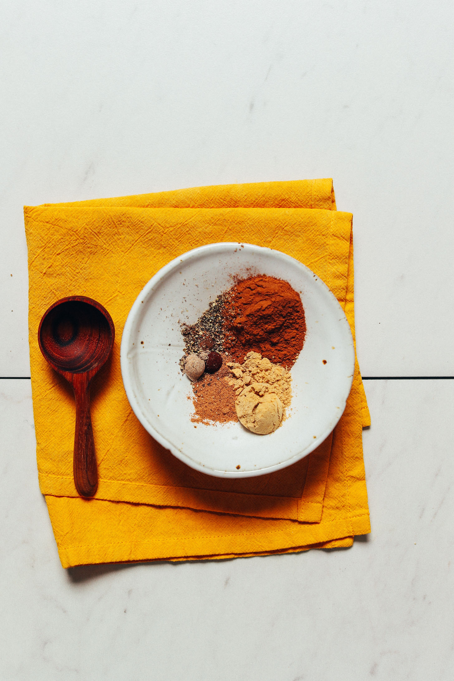 Spoon beside a bowl of spices for making Pumpkin Pie Spice