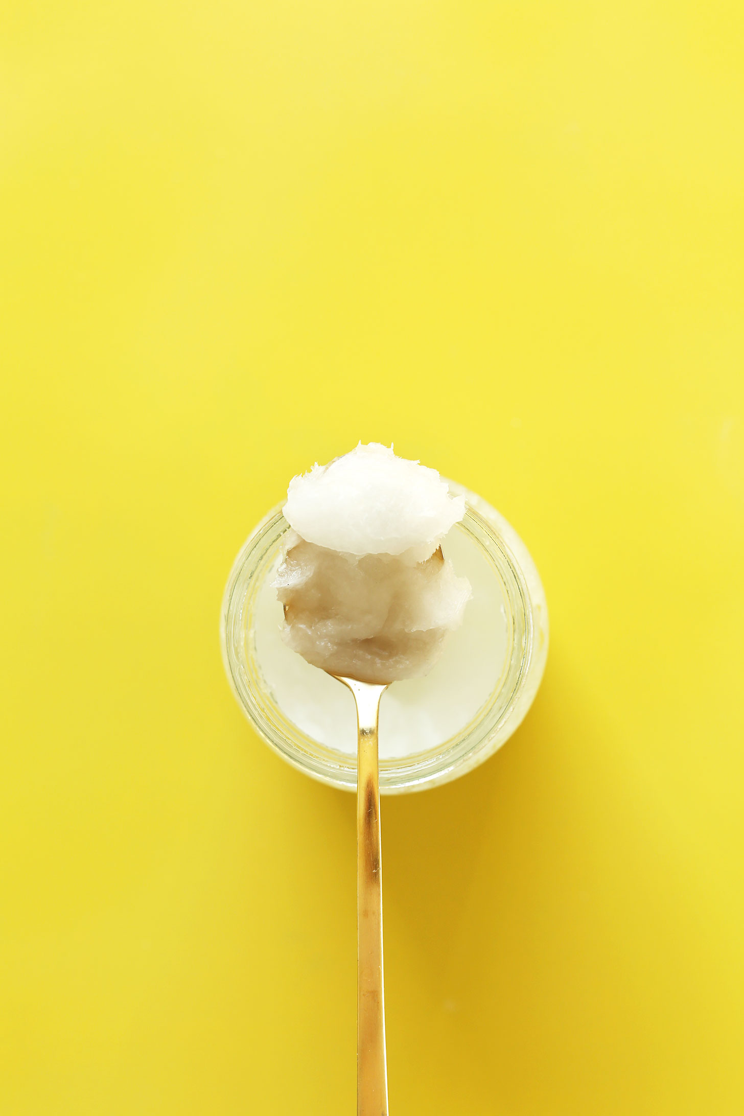 Spoonful of coconut oil resting on a jar