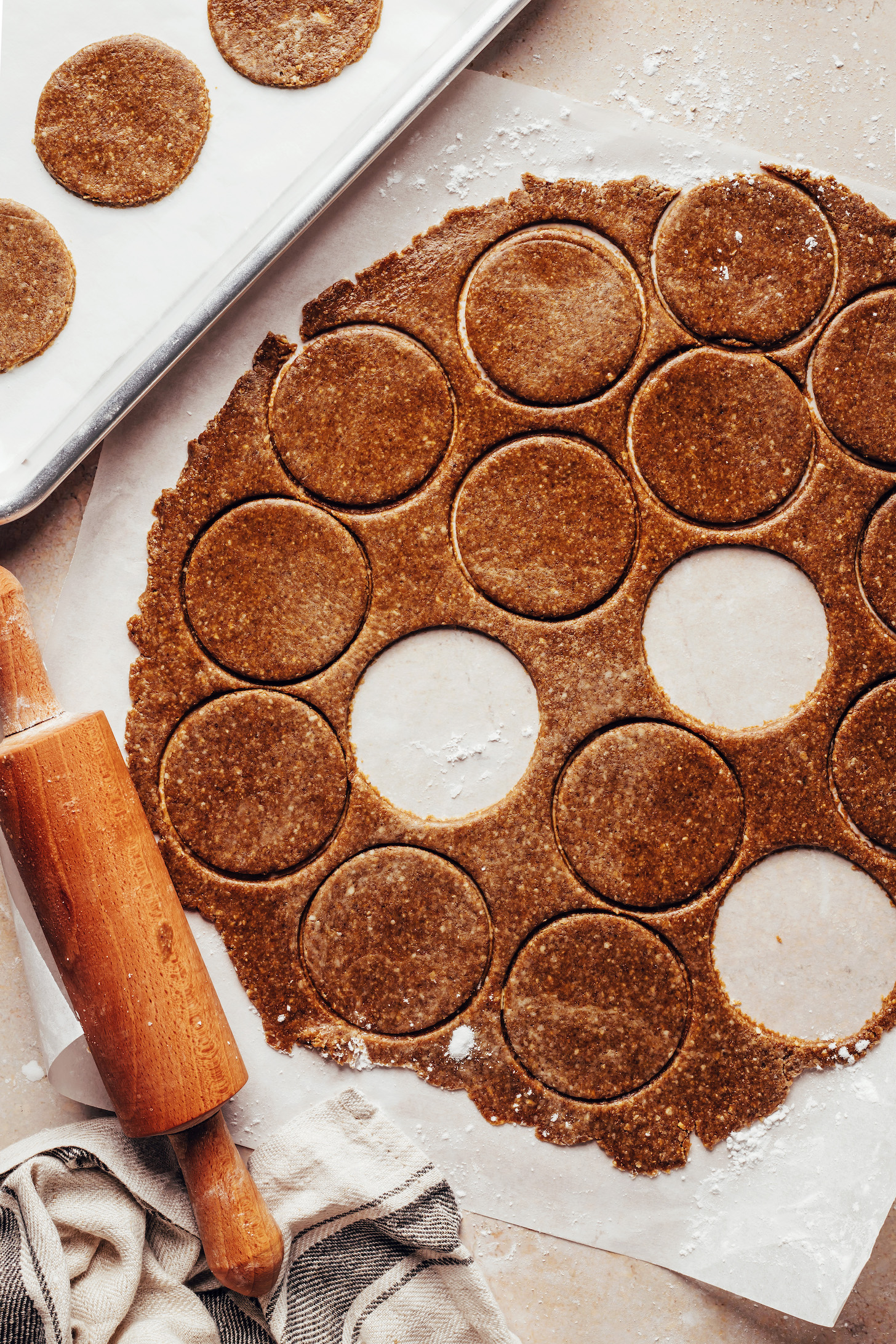 Mini rolling pin next to gingersnap dough cut into small circles with a cookie cutter