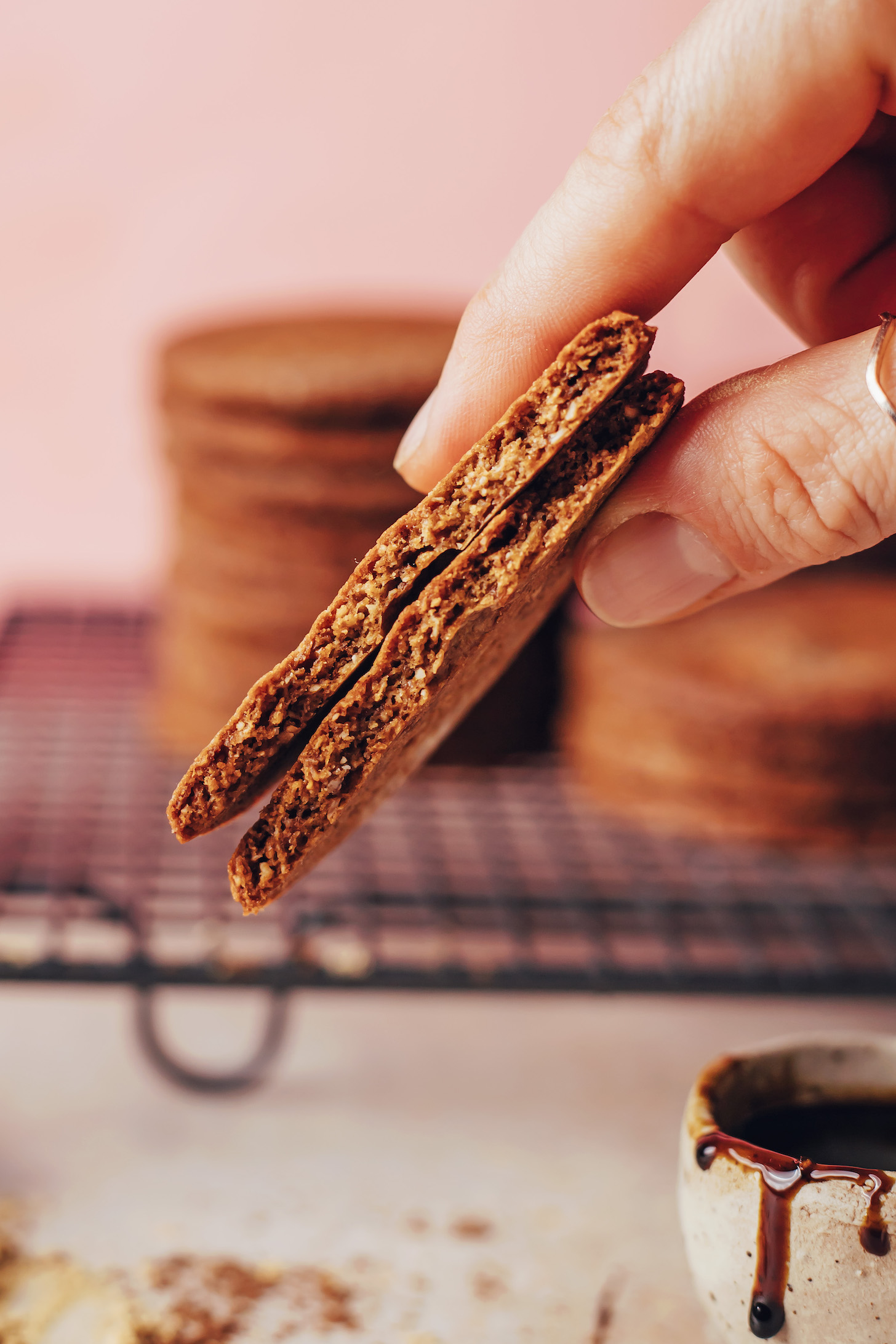 Holding two halves of a gingersnap cookie to show the crispy inner texture