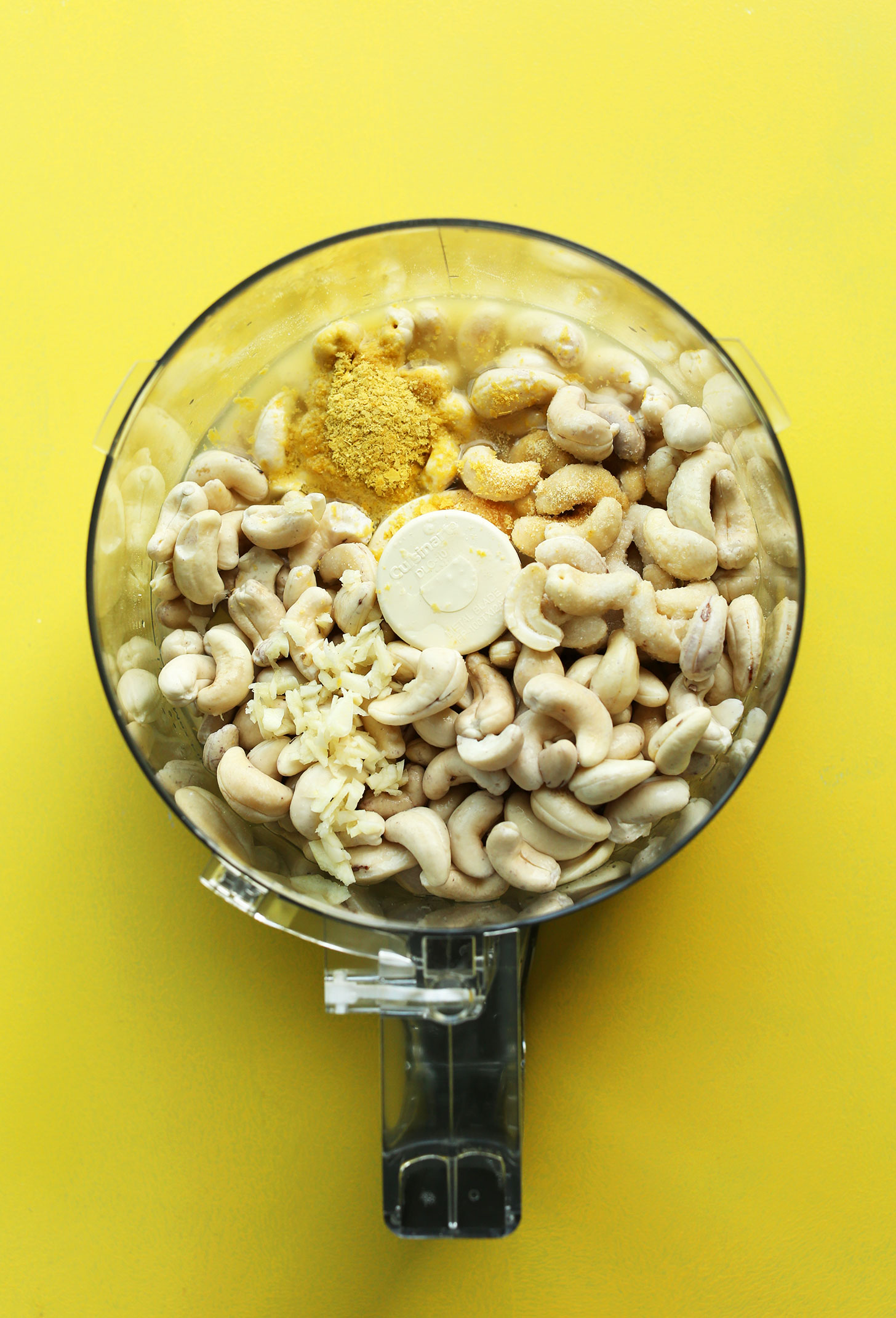 Food processor with cashews and other ingredients for making our easy Vegan Cheese recipe