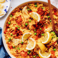 Pan of vegan paella topped with lemon wedges