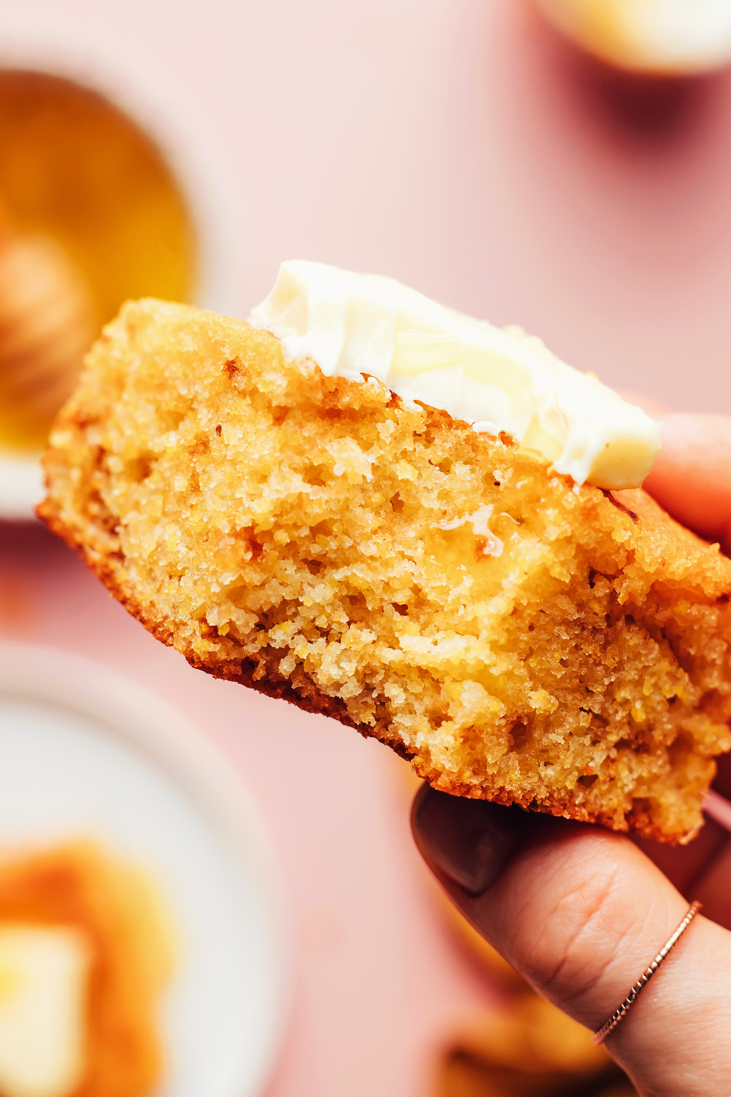 Close up photo of a slice of gluten-free cornbread topped with butter and honey