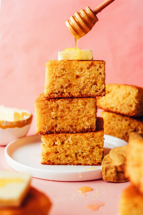 Stack of slices of gluten-free cornbread topped with butter and a drizzle of honey