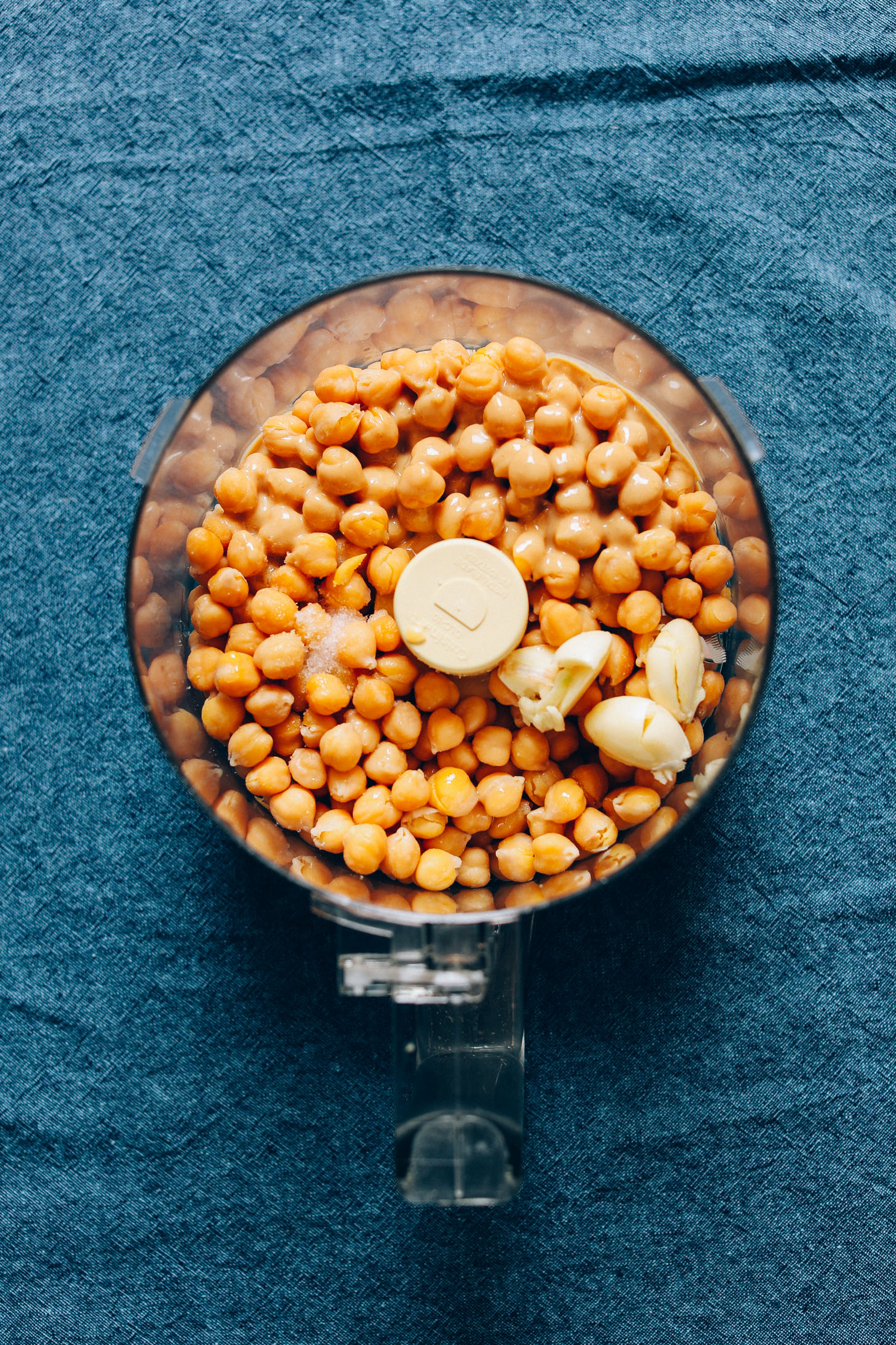 Food processor with ingredients for making gluten-free vegan hummus from scratch