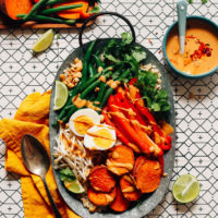 Tray of our delicious Gado Gado recipe beside a bowl of Spicy Peanut Sauce