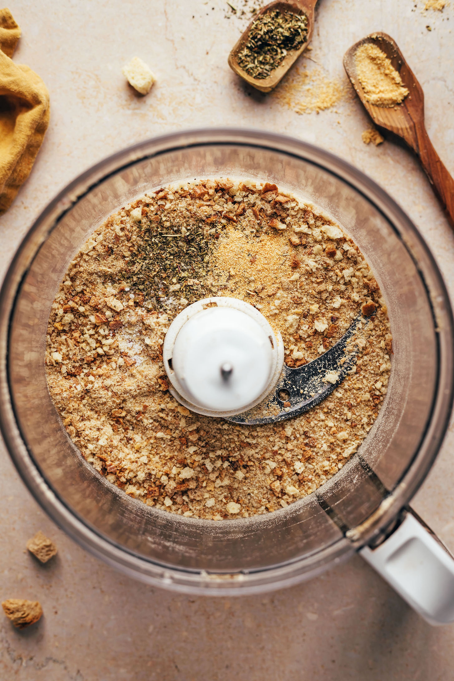 Homemade breadcrumbs in a food processor with garlic powder, Italian herbs, and salt