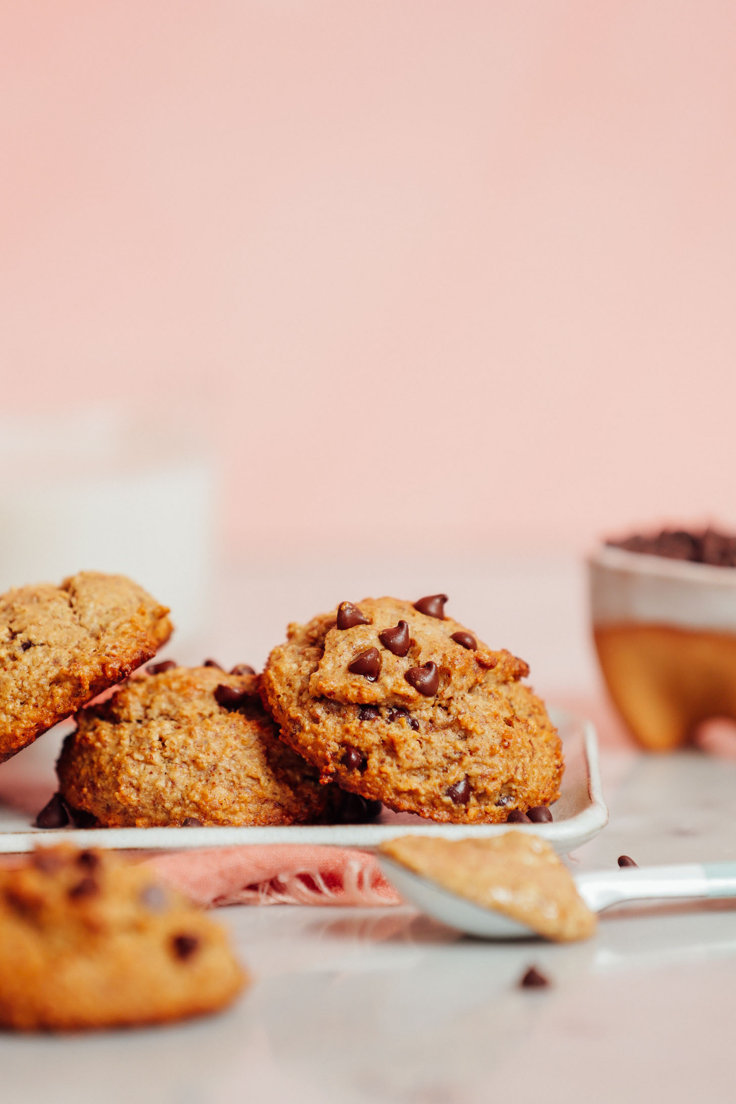 Spoonful of almond butter in front of a plate of Banana Chocolate Chip Cookies