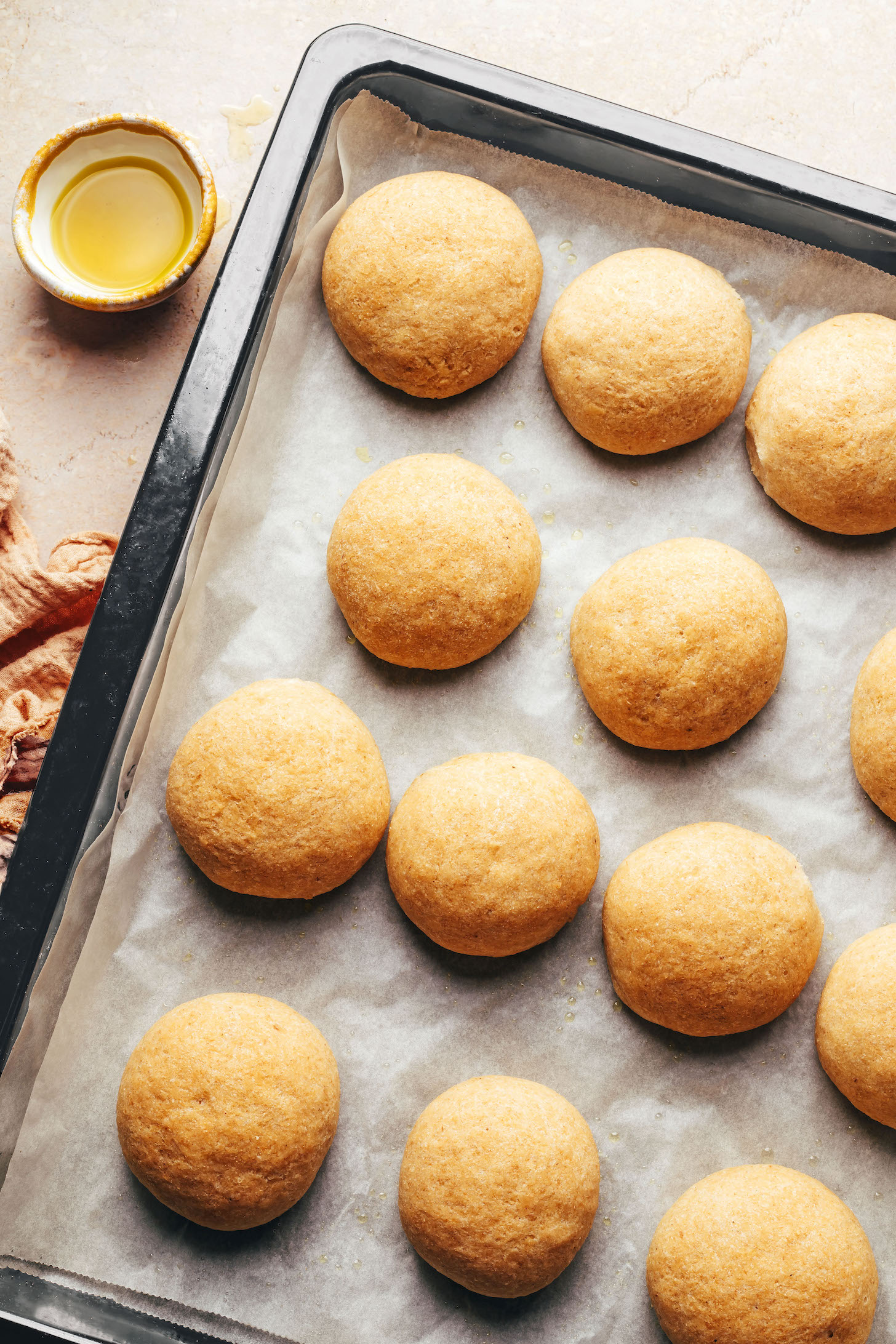 Freshly baked gluten-free vegan dinner rolls on a parchment-lined baking sheet