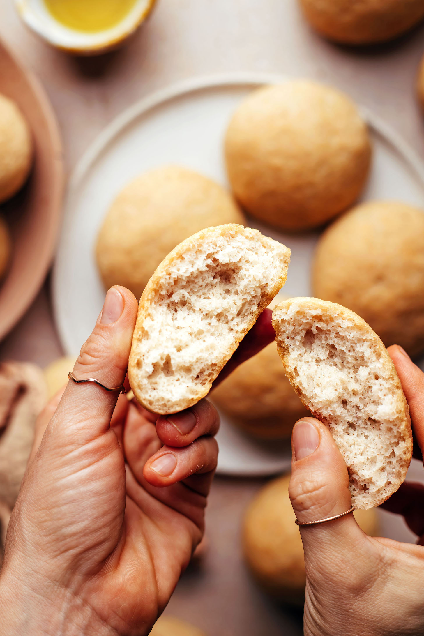 Hands holding a broken apart gluten-free dinner roll 