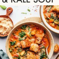 Bowls of our creamy Tuscan white bean and kale soup next to a small dish of vegan parmesan