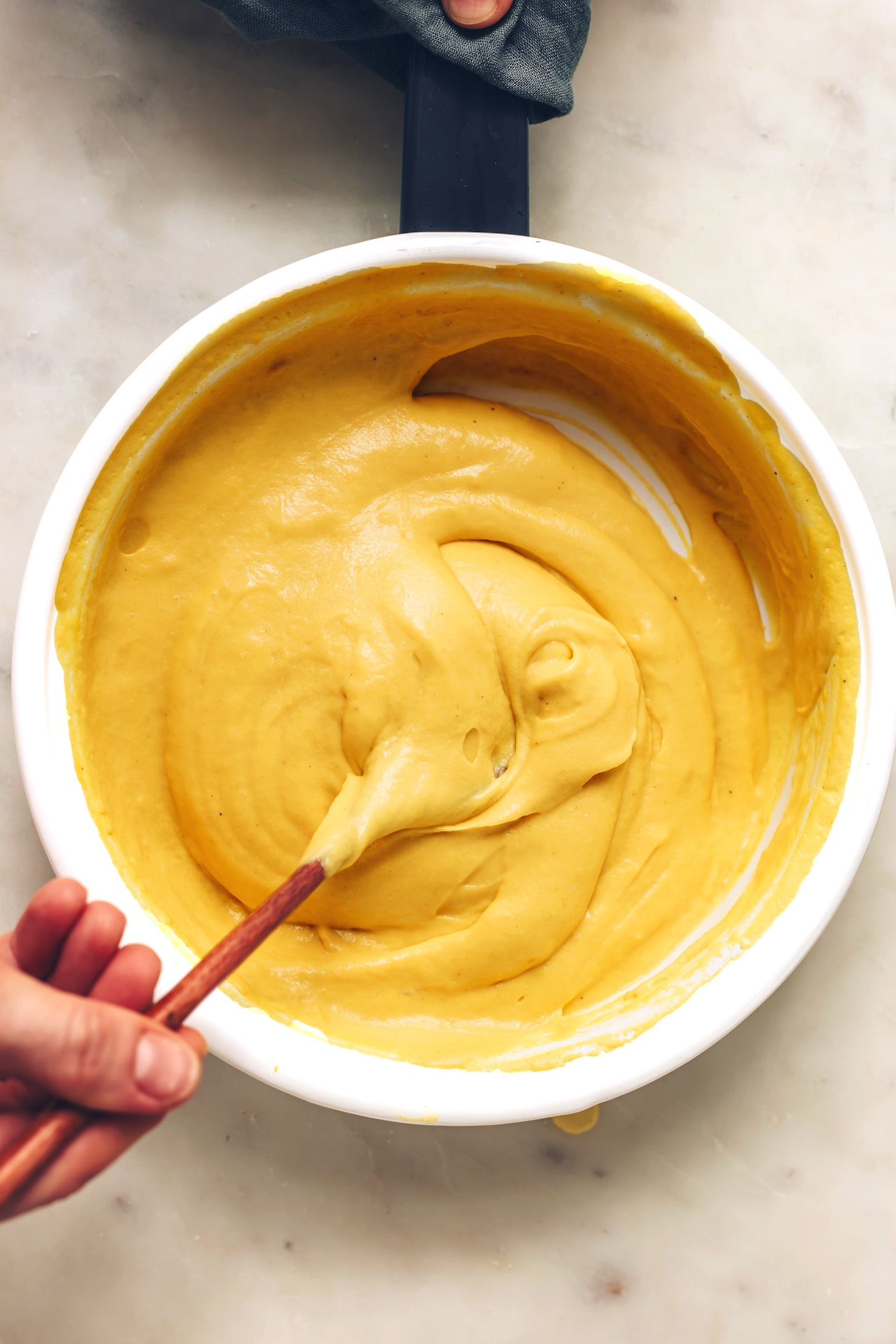 Stirring a pan of homemade vegan cheddar cheese