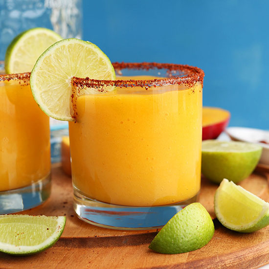 Wood cutting board with lime wedges and Chili Lime Mango Margaritas