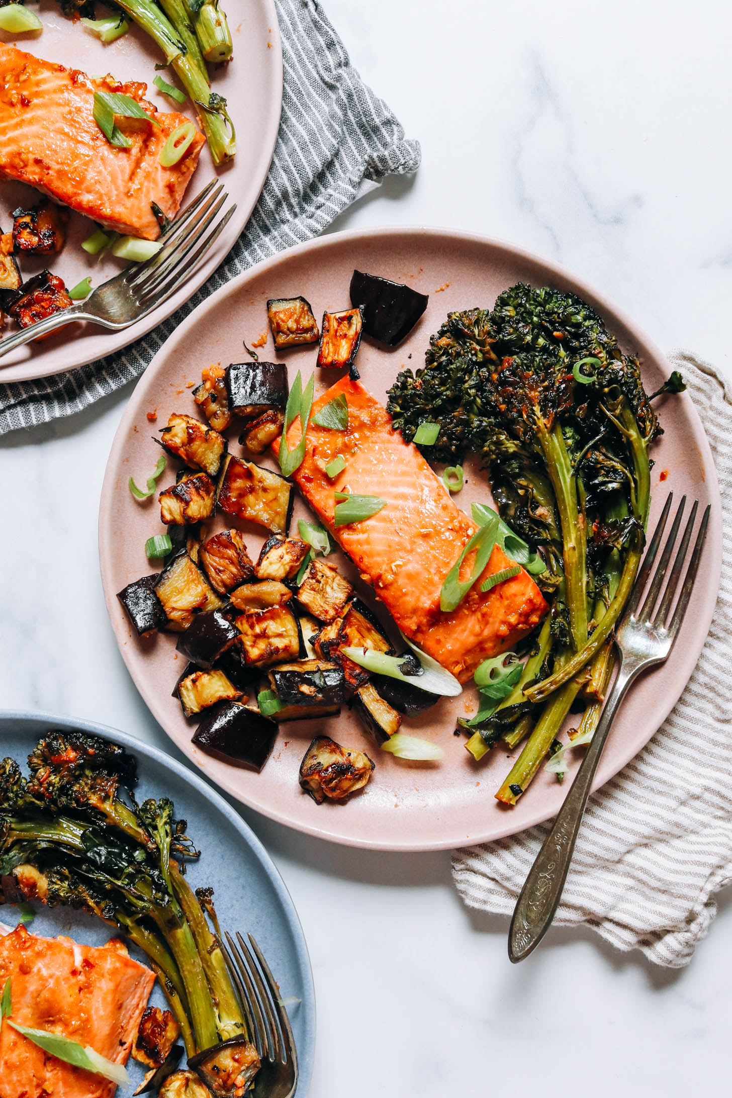 Plates of miso-glazed salmon and veggies topped with green onion