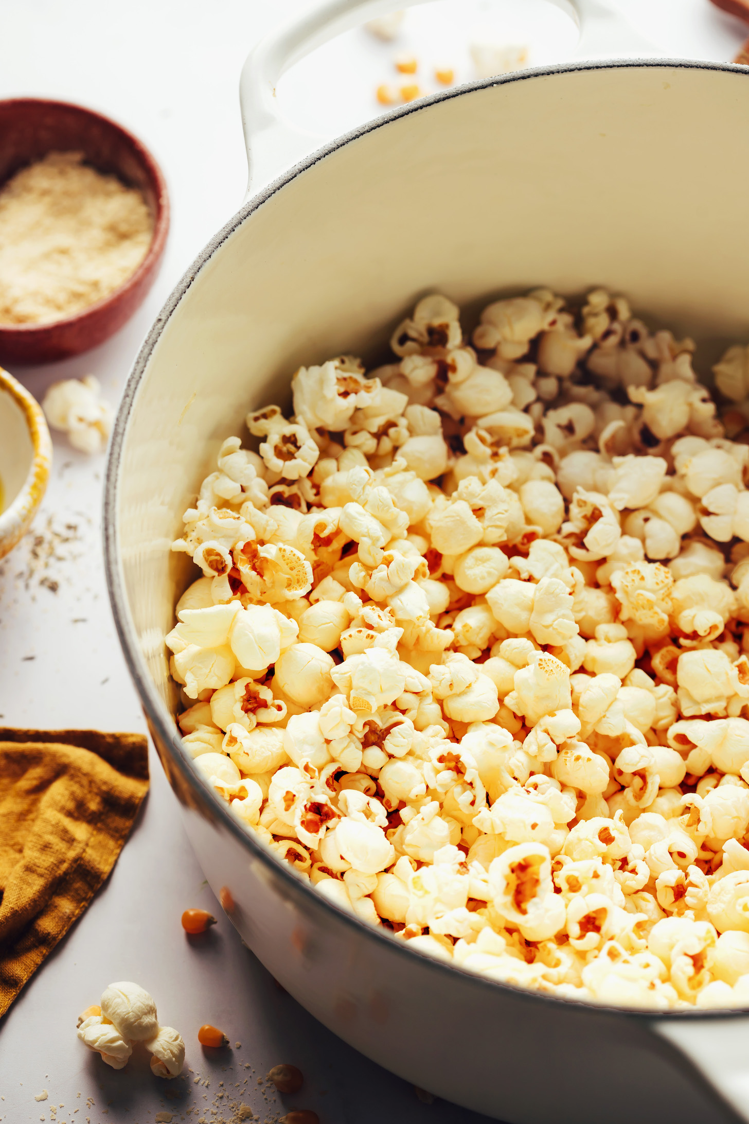 Close up shot of popped popcorn in a pot next to a bowl of nutritional yeast