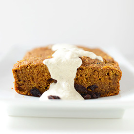 Ceramic platter with a loaf of Vegan Pumpkin Currant Bread drizzled with frosting