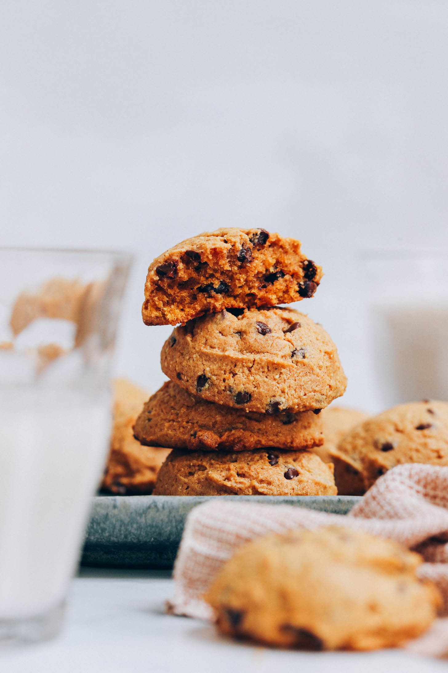 Stack of vegan gluten-free pumpkin chocolate chip cookies with the top one broken apart to show the texture