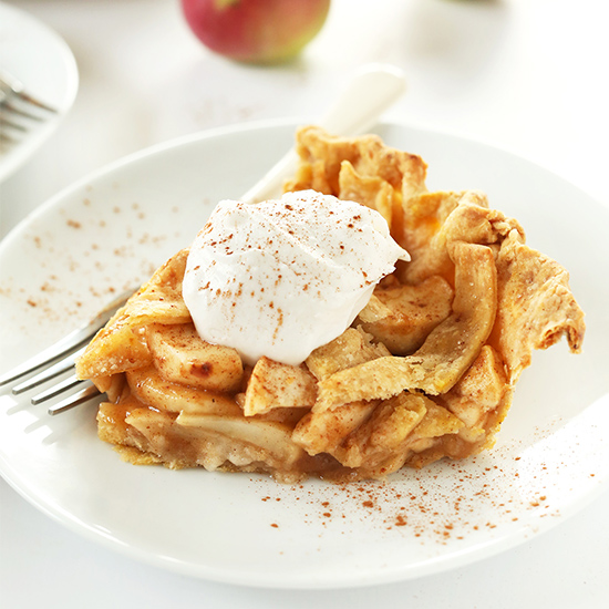 Plate with a slice of Pumpkin Spiced Apple Pie topped with vegan whipped cream and pumpkin pie spice