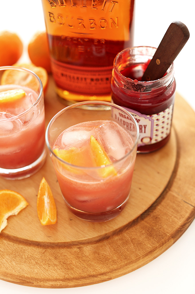 Glasses of Raspberry Jam Bourbon Smash on a wood cutting board