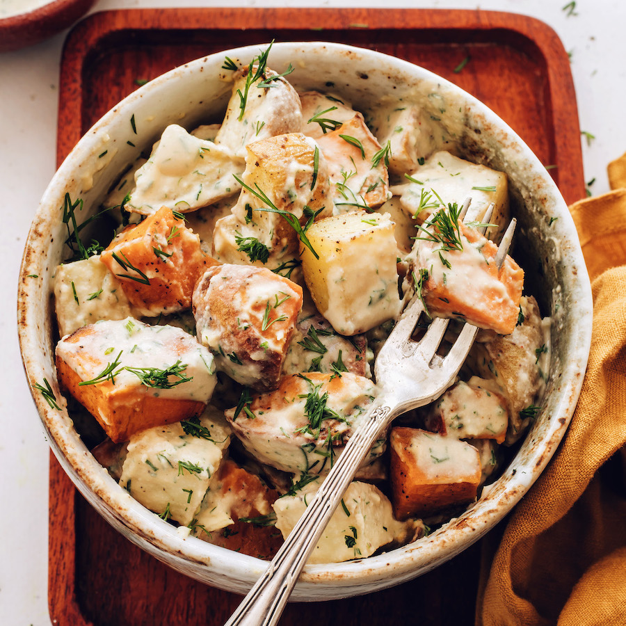 Fork spearing a potato in a bowl of our roasted potato salad recipe