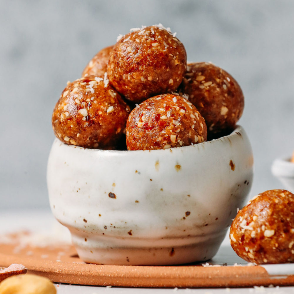 Bowl filled with Salted Cashew Caramel Energy Bites topped with shredded coconut