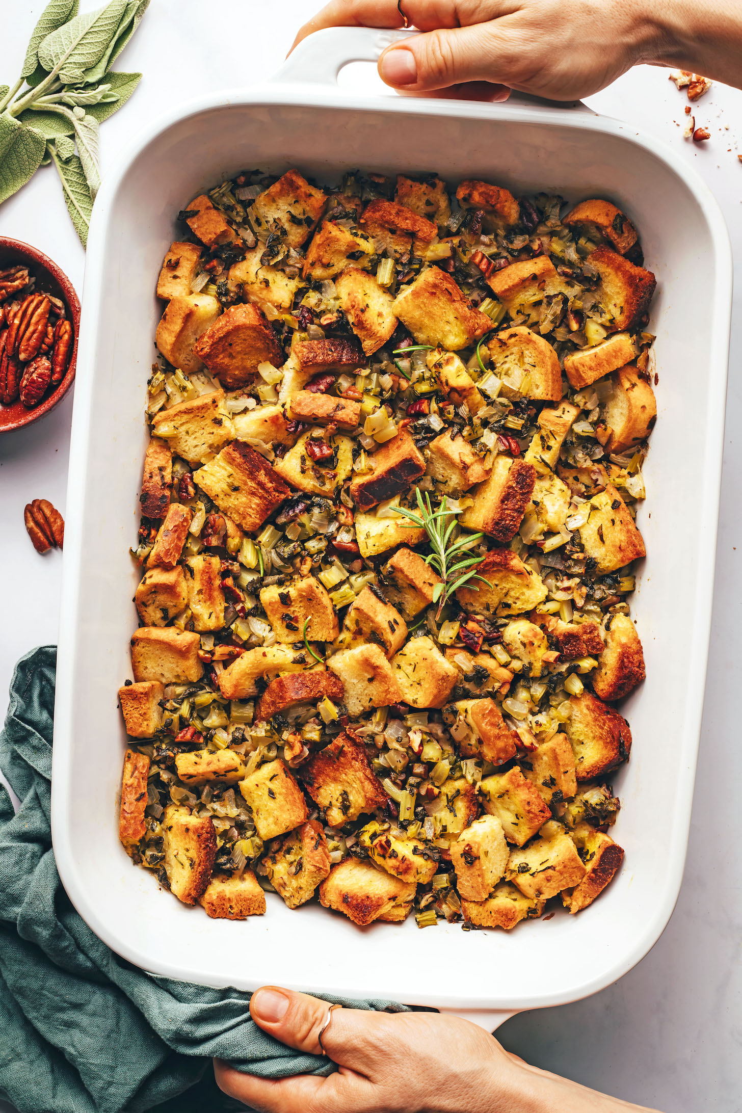 Hands holding a pan of baked gluten-free vegan stuffing