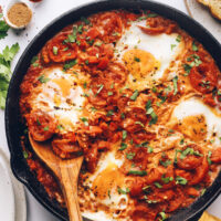 Wooden spoon in a skillet of shakshuka