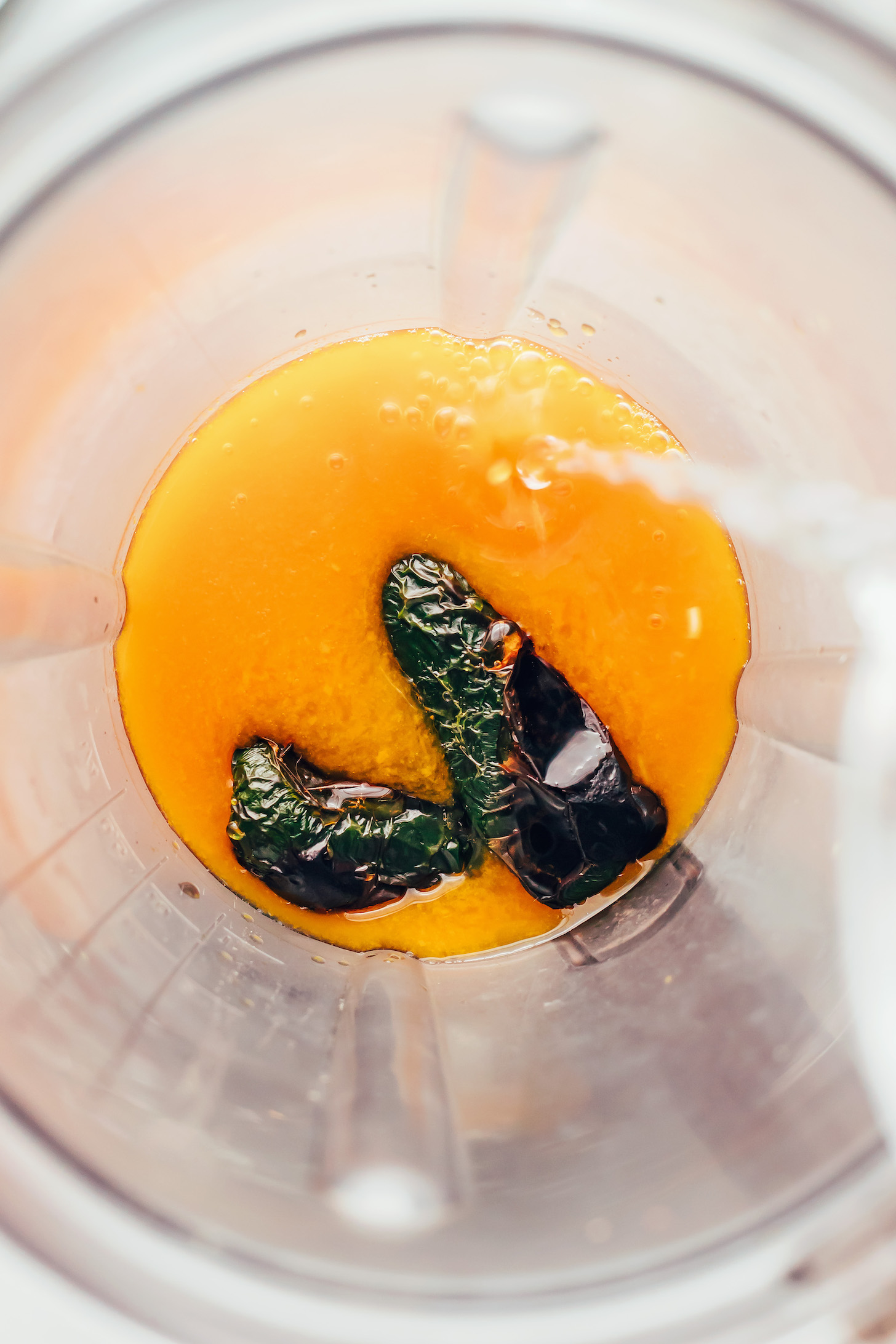 Pouring water into a blender with passion fruit purée, charred jalapeños, lime juice, and agave