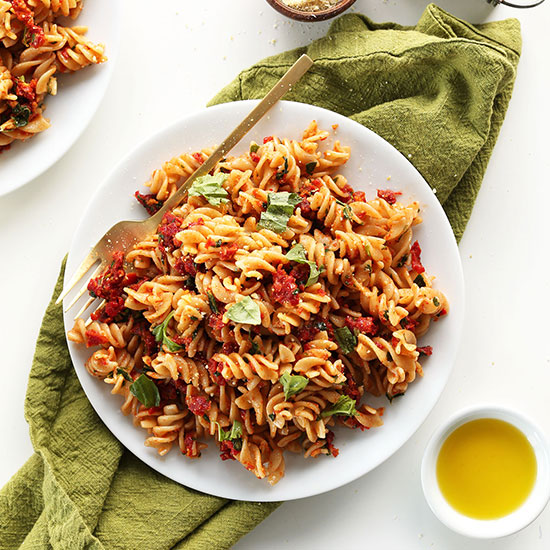 Big plate of Gluten-Free Sun-Dried Tomato Pesto Pasta topped with fresh basil