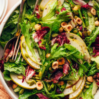 Serving utensils resting in a bowl of our Perfect Thanksgiving Salad recipe